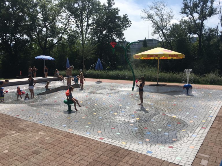 Begeisterte Kinder "testen" das neue Schwimmbecken aus Granitsteinen gepflästert in Bern Belp.